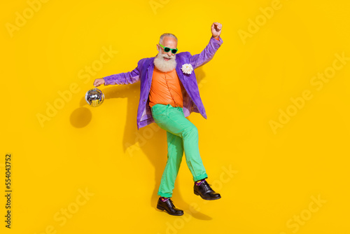 Full length photo of pretty attractive guy dressed violet velvet jacket holding disco ball dancing isolated yellow color background