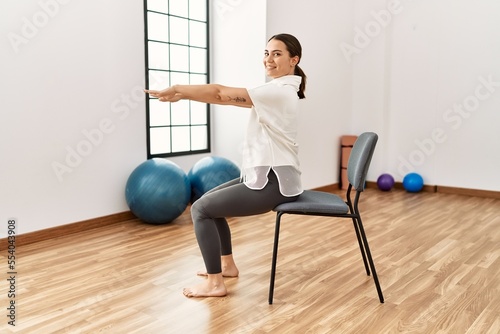 Young hispanic woman smiling confident stretching at sport center.