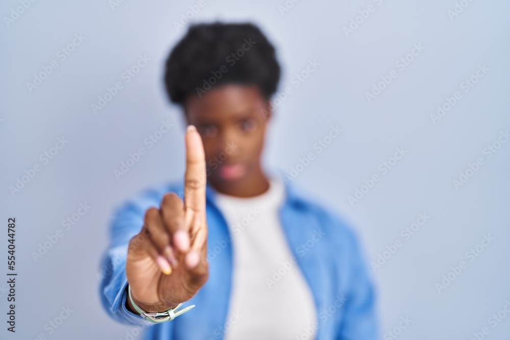 African american woman standing over blue background pointing with finger up and angry expression, showing no gesture African american woman standing over blue background pointing with finger up and angry expression, showing no gesture