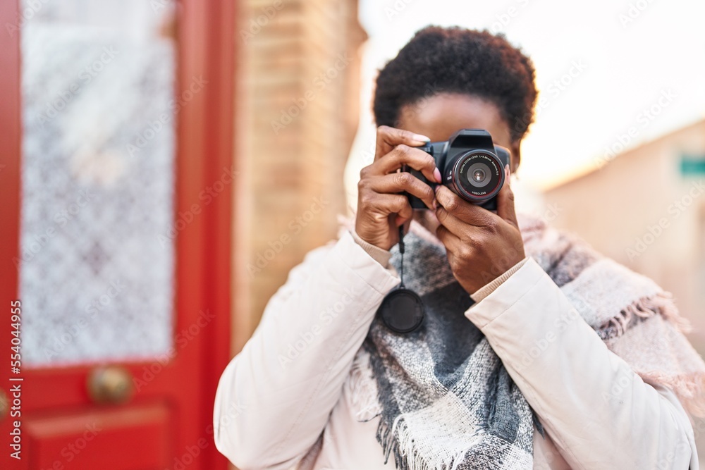 African american woman smiling confident using professional camera at street