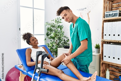 Man and woman wearing physiotherapist uniform having rehab session massaging leg at physiotherapy clinic © Krakenimages.com