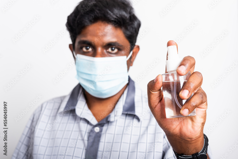 Closeup Asian black man wearing protective face mask fear in eye holding show sanitizer spray, hygiene prevention COVID-19 virus or coronavirus protection concept isolated on white background Closeup Asian black man wearing protective face mask fear in eye holding show sanitizer spray, hygiene prevention COVID-19 virus or coronavirus protection concept isolated on white background