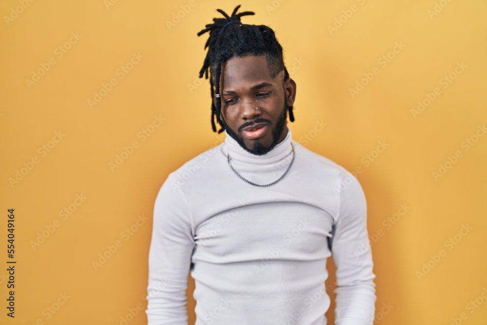 African man with dreadlocks wearing turtleneck sweater over yellow background depressed and worry for distress, crying angry and afraid. sad expression. African man with dreadlocks wearing turtleneck sweater over yellow background depressed and worry for distress, crying angry and afraid. sad expression.