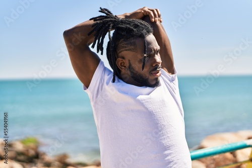 African american woman shirtless stretching arms at seaside