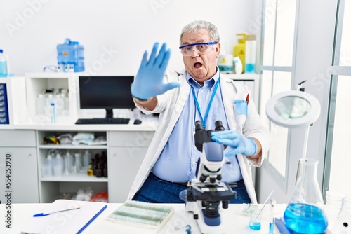 Senior caucasian man working at scientist laboratory doing stop gesture with hands palms  angry and frustration expression