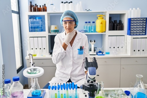Brunette woman working at scientist laboratory touching painful neck  sore throat for flu  clod and infection