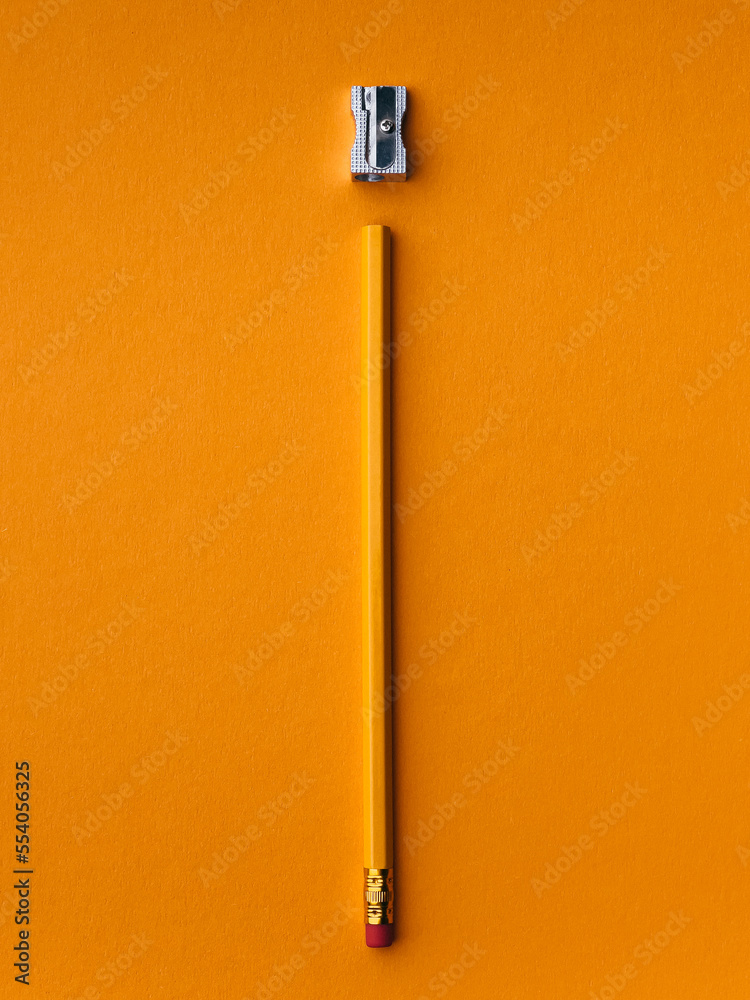 Stationery on office table. Yellow pencils with red rubbered tip on orange paper with metallic sharpener Stationery on office table. Yellow pencils with red rubbered tip on orange paper with metallic sharpener