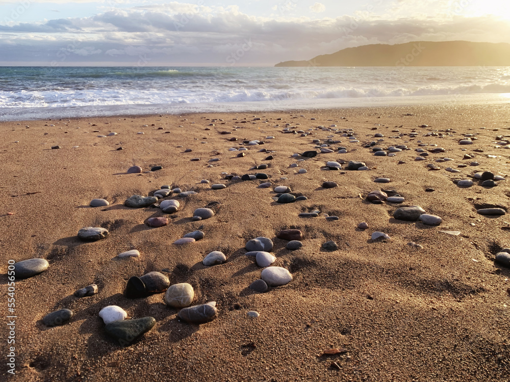 Beauty sunset lights over the sea and coastline with sand and wet pebbles Beauty sunset lights over the sea and coastline with sand and wet pebbles