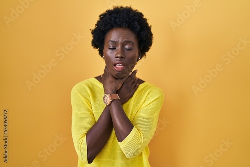 African young woman standing over yellow studio shouting suffocate because painful strangle. health problem. asphyxiate and suicide concept. © Krakenimages.com