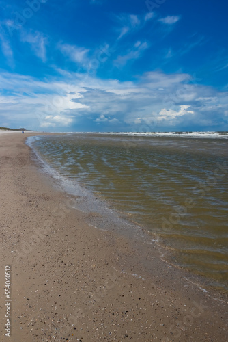 Sandy beach of Wangerooge island on the coast of Germany with shells on the North sea. National park  world natural heritage and perfect place for beachcombing and recreation. Windy day with blue sky.