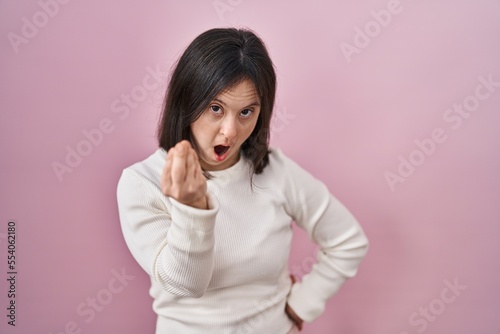 Woman with down syndrome standing over pink background doing italian gesture with hand and fingers confident expression © Krakenimages.com