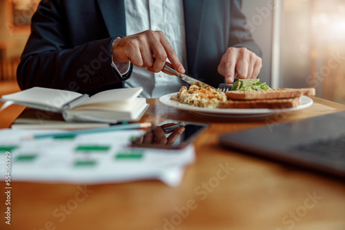 Close up of businessman taking a breakfast before starting working day in cafe