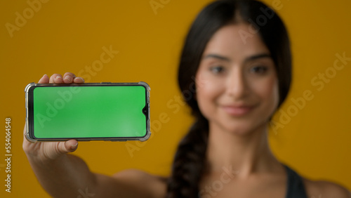 Obraz na plátně Close up Indian ethnic smiling woman female girl in yellow studio holding phone