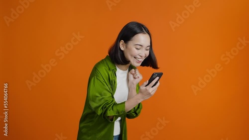 Asian woman looks at mobile phone and exclaims joyfully photo
