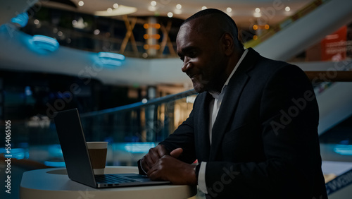 Middle-aged 50s ethnic man African worker manager typing wireless computer at table. Adult senior mature businessman working with laptop male entrepreneur distant job financial startup IT work online