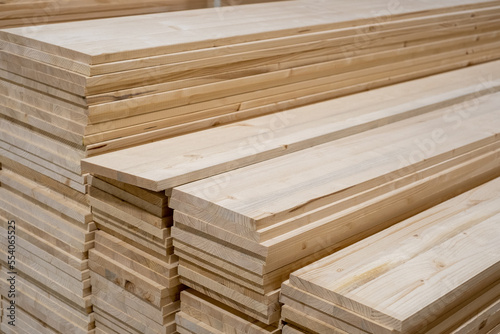 Stacks of pine wood planks in a store or on building site. Natural rough wooden boards boards, lumber, industrial wood, timber