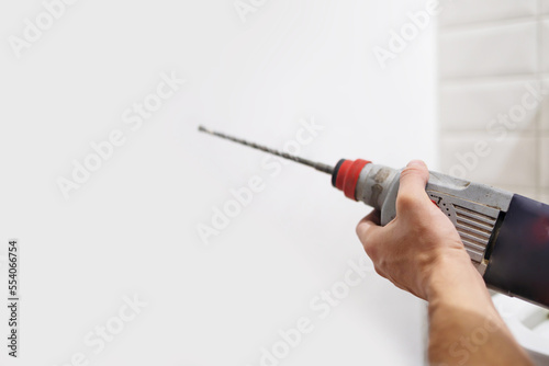 Drilling a white wall with a drill close-up.