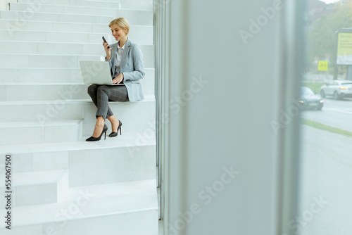 Businesswoman using mobile phone on modern office stairs