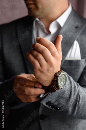 A man dresses and adjusts a watch on his wrist.