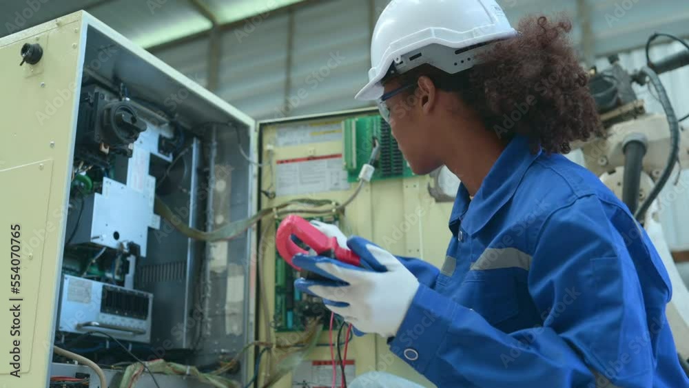 Experienced female electrical engineer The electrical system of the welding robot's electrical control system is being checked and the operation is tested after hard work.