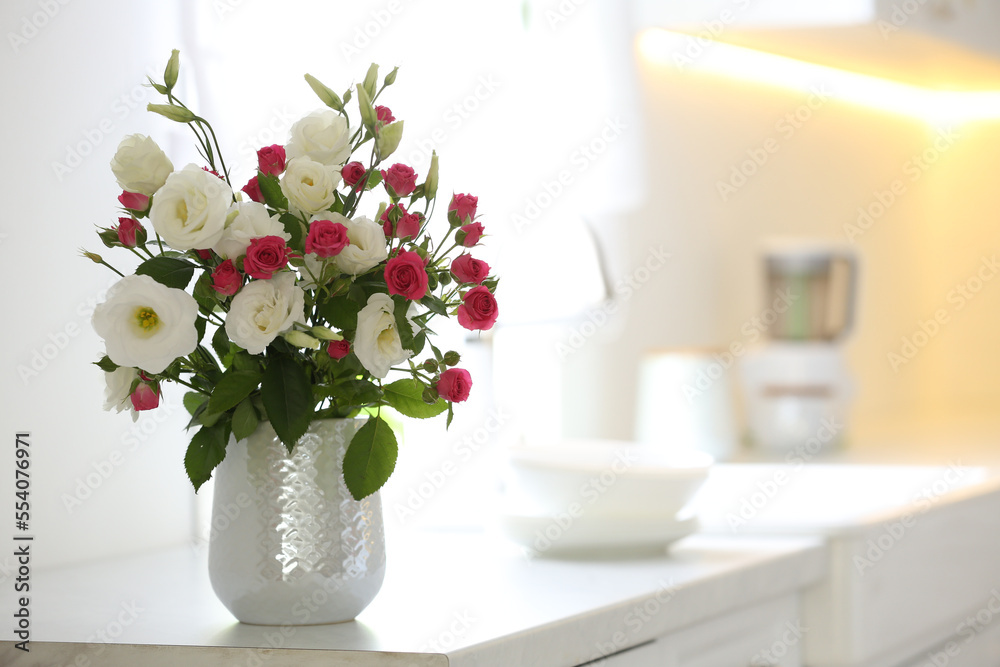 Vase with fresh flowers on table in kitchen. Space for text