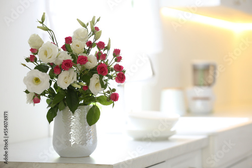 Vase with fresh flowers on table in kitchen. Space for text