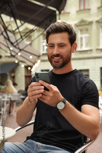 Handsome man using smartphone in outdoor cafe