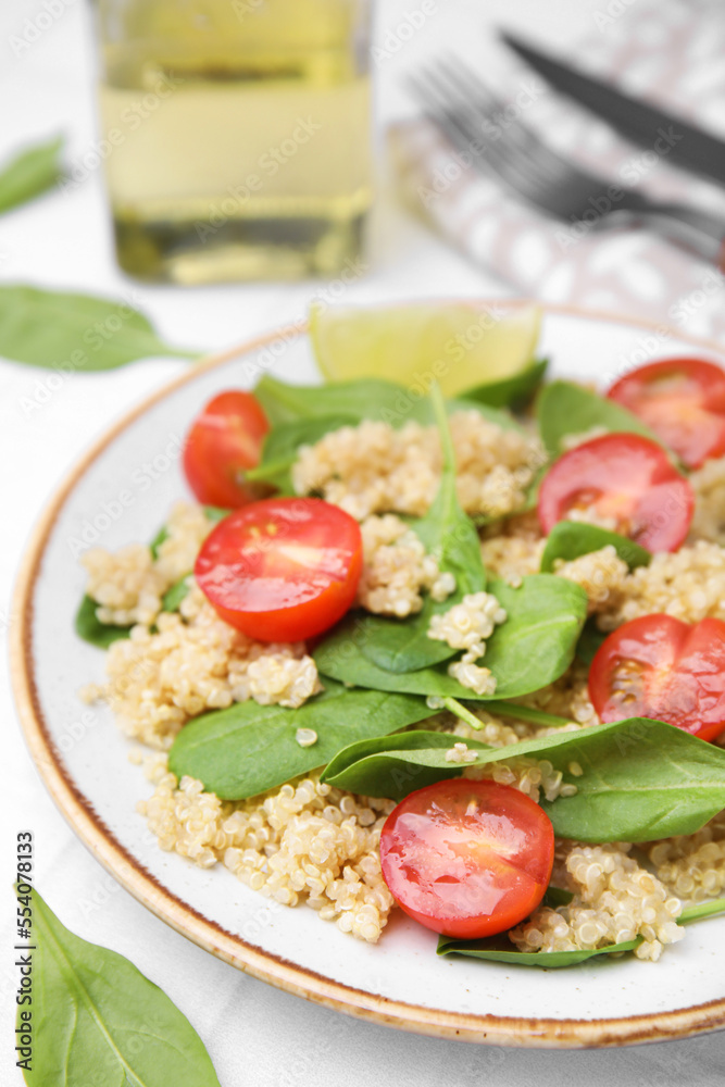 Delicious quinoa salad with tomatoes and spinach leaves served on white table, closeup Delicious quinoa salad with tomatoes and spinach leaves served on white table, closeup
