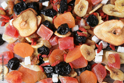 Pile of different tasty dried fruits on wooden table, flat lay