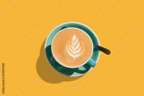 Aromatic coffee in turquoise cup on yellow background, top view