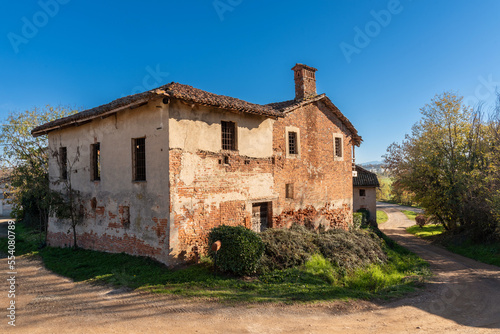 Ancient abandoned farmhouse typical of the countryside near a country road in the province of Cuneo, Piedmont, Italy