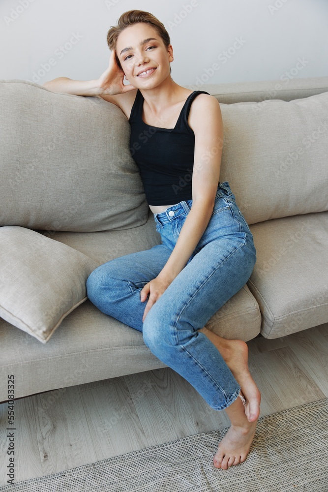 Young woman with short haircut hair having fun at home on the couch smile and happiness, vacation at home, natural posing without filters, free copy space Young woman with short haircut hair having fun at home on the couch smile and happiness, vacation at home, natural posing without filters, free copy space