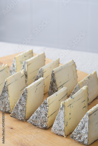 Blue cheese pieces on a wooden board, selective focus. Dorblu danishn blue roquefort stilton craft cheese.