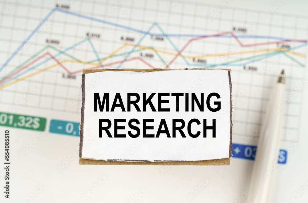 Against the background of business graphics and pens, a sign with the inscription - MARKETING RESEARCH Against the background of business graphics and pens, a sign with the inscription - MARKETING RESEARCH