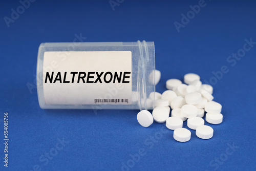 On a blue surface are pills and a dusty jar with the inscription - Naltrexone photo