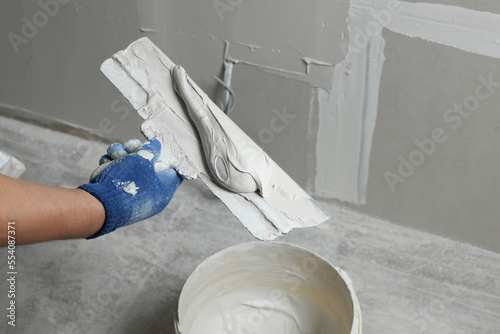 Принти на полотні Professional worker holding putty knife with plaster indoors, closeup