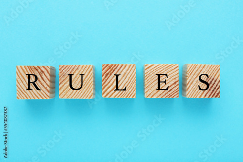 Word Rules made of wooden cubes with letters on light blue background, flat lay