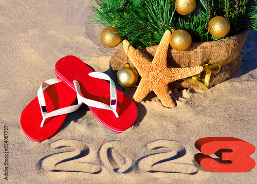 New Year 2023 on the beach. 3D. Christmas tree, starfish and slippers in sand