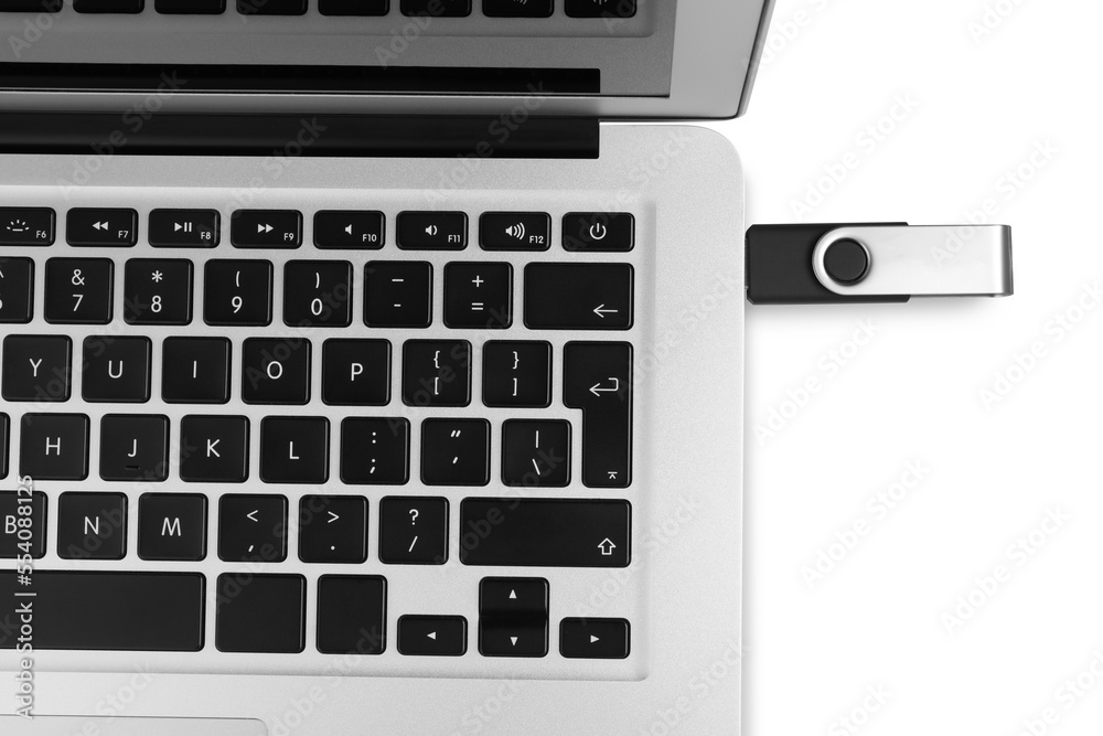 Modern usb flash drive attached into laptop on white background, top view Modern usb flash drive attached into laptop on white background, top view