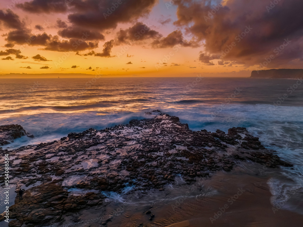 Obraz premium Surfs up sunrise at the seaside with scattered clouds