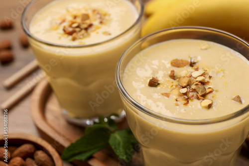 Tasty banana smoothie with almond on wooden table, closeup. Space for text © New Africa