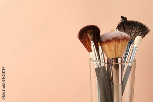Set of professional makeup brushes on beige background. Space for text