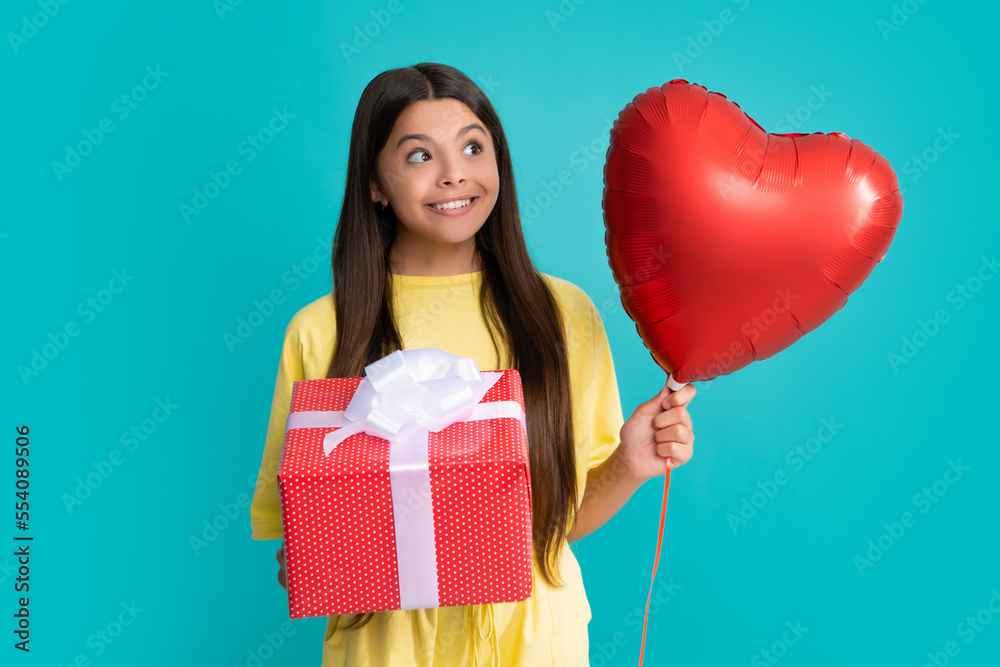 Teenager child with gift box. Present for holidays. Happy birthday, Valentines day. Kid hold present box, love valentines heart balloon. Happy girl face, positive and smiling emotions. Teenager child with gift box. Present for holidays. Happy birthday, Valentines day. Kid hold present box, love valentines heart balloon. Happy girl face, positive and smiling emotions.