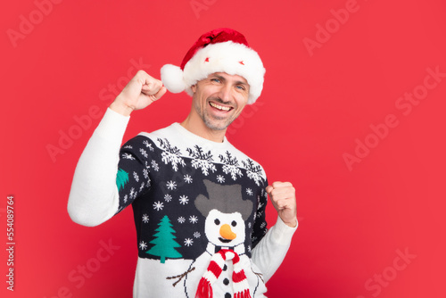 Portrait of man scream wow omg point thumb at copy space hear incredible news of christmas time theme party wear pullover isolated on red studio background.