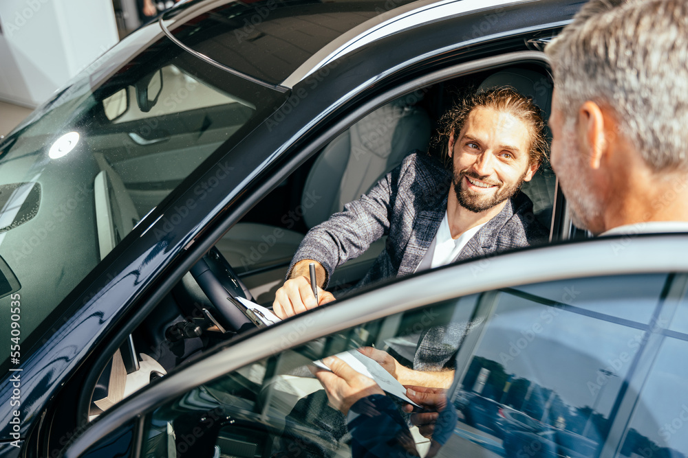 Φωτογραφία Happy professional salesman and customer sign documents for the sale or lease of a car