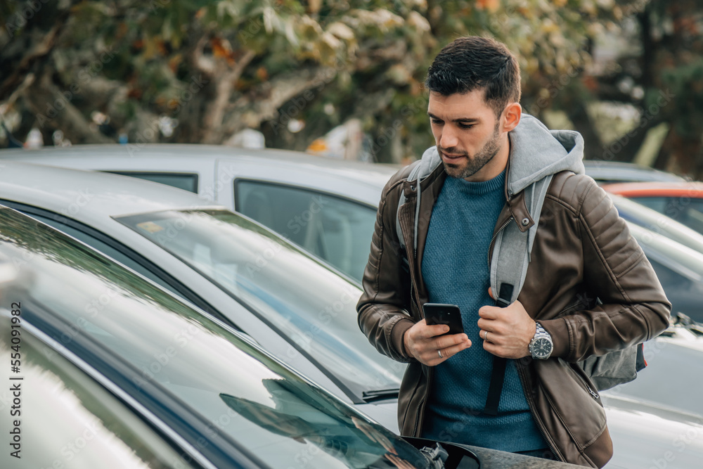 man with mobile phone looking and buying car