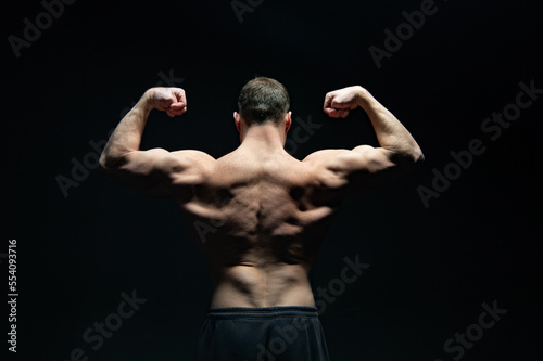 bodybuilder with muscular back isolated on black background. muscular bodybuilder