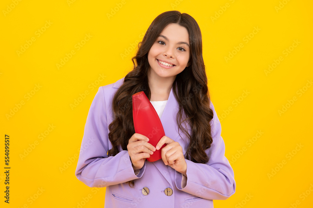 Child teen girl with shampoos conditioners and shower gel. Long hair care of teenager. Presenting cosmetic product, shampoo bottle. Happy teenager, positive and smiling emotions of teen girl. Child teen girl with shampoos conditioners and shower gel. Long hair care of teenager. Presenting cosmetic product, shampoo bottle. Happy teenager, positive and smiling emotions of teen girl.