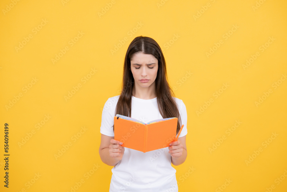 Sad angry young woman college student holding book on isolated gray background. Model emotionally showing facial expressions. Sad angry young woman college student holding book on isolated gray background. Model emotionally showing facial expressions.
