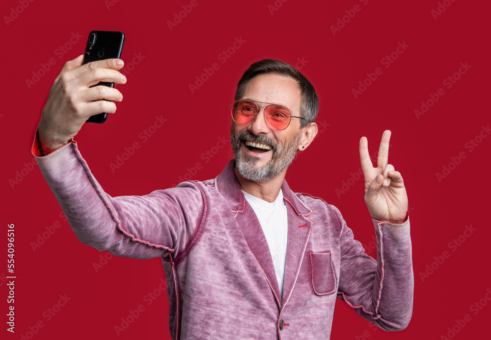 stylish man blogging on phone isolated on red background, peace. man make selfie stylish man blogging on phone isolated on red background, peace. man make selfie